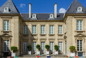 Facade of the Museum of Decorative Arts and Design in Bordeaux, a classical stone building with mansard roofs, mullioned windows and a garden with topiary box shrubs