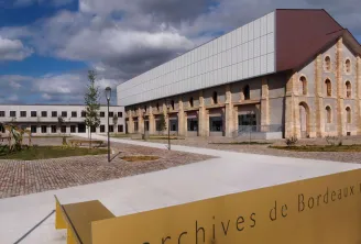 Modern Archives of Bordeaux Métropole building featuring a stone facade and contemporary roofing, surrounded by a paved courtyard and green spaces.