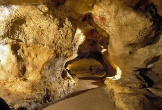 Interior of Pair-non-Pair cave near Bordeaux, displaying illuminated limestone walls and a natural opening with daylight