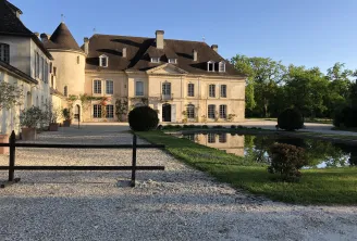 Château Bouscaut in Bordeaux, an elegant wine estate featuring a stone facade, mansard roofs, and classical architectural details, surrounded by a reflecting pond and manicured grounds.
