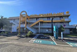 Première Classe Hotel Bordeaux West Eysines building exterior with golden signage, external staircase, and electric vehicle charging stations in the parking lot.