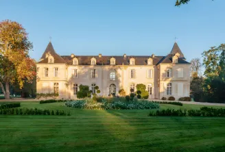 Château de Reignac near Bordeaux, an elegant neoclassical château featuring a cream-colored facade, pointed slate roofs with two towers, set in a verdant park with autumn foliage.