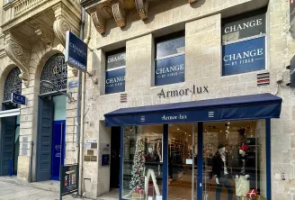 Armor.lux storefront with 'Change at Fidso' signage displayed in shop windows, located on rue de l'Intendance in Bordeaux, featuring Haussmann-style stone architecture.