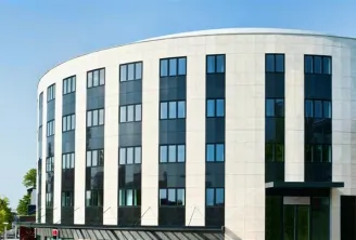 Modern curved facade of a white and black residential building with regular rows of windows, located in Talence near Bordeaux