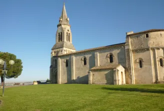 Saint-Siméon Church in Bordeaux, a stone religious building with a pointed steeple, surrounded by green lawn and parkland overlooking the city.