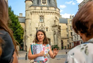 Tour guide holding a historical map explaining architecture in front of Pey-Berland Tower in Bordeaux