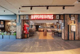 Hippopotamus restaurant storefront in Bordeaux featuring red neon signage, rustic wooden facade, service counter and interior decor visible from the entrance