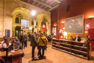 Interior of Utopia cinema in Bordeaux featuring distinctive Gothic vaulted ceilings, red and gold decor, visitors in the lobby, and the reception desk.