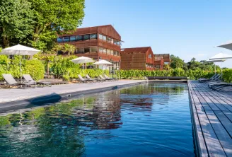 Outdoor swimming pool at Le Saint-James hotel in Bordeaux featuring red brick buildings, sun loungers, umbrellas, and wooden deck