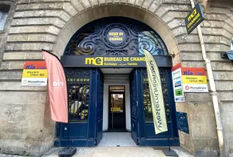 Storefront of Monex Exchange currency exchange office in Bordeaux on Victor Hugo street, featuring ornate blue doors with gold details, yellow signage, and Western Union and MoneyGram advertisements.