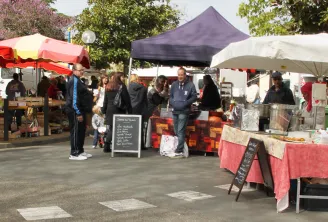 Bègles market in Bordeaux featuring market stalls with red, white and black canopies, vendors and shoppers browsing local and artisanal products.