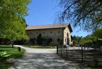 The Moulineau, a historic stone mill with brown roof located in René Canivenc park in Bordeaux, surrounded by green grass and trees.