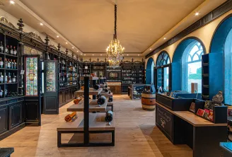 Elegant wine cellar interior with black cabinetry, bottle displays, golden chandelier, blue arches and wine exhibition tables at Château Pape Clément in Bordeaux