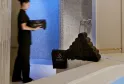Interior of the Hôtel de Sèze spa in Bordeaux featuring a staff member in black attire near a blue water basin, stacked black towels, and textured tile panels in the background.