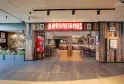 Hippopotamus restaurant storefront in Bordeaux featuring a red neon sign, light wooden facade with glass entrance, located in a modern shopping center.