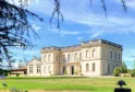 Château La Chèze in Bordeaux, a neoclassical stone mansion with symmetrical facade, situated in a lush green park surrounded by ancient trees