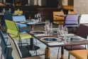 Modern restaurant interior with set tables, colorful chairs in yellow, blue, orange and purple, and elegant tableware at La Zoologie hotel restaurant in Bordeaux.