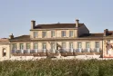 Classic stone facade of a Bordeaux mansion with wrought iron balcony overlooking vineyards in Bordeaux.