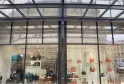 Storefront of Massip Maroquinerie in Bordeaux displaying leather handbags and accessories in various colors through glass windows beneath an architectural glass canopy.