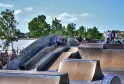 Bordeaux skate park featuring concrete ramps with skaters and spectators, overlooking the Garonne River and city architecture