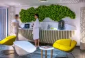 Modern reception area of Spa Dock G6 in Bordeaux featuring a green living wall, contemporary desk, and yellow lounge chairs