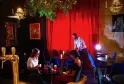 Interior of Théâtre des Chartrons in Bordeaux featuring three people in an elegant bar with red walls, blue furniture, sophisticated lighting and plant decoration.
