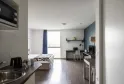 Modern studio apartment at Ténéo Aparthotel in Bordeaux-Maritime featuring a bed, equipped kitchenette, work area, large window with balcony and contemporary decor