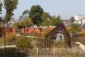 Bordeaux's Parc aux Angéliques featuring a wooden pergola, autumn foliage, white fence in foreground, and the Garonne river in the background