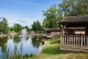 Holiday village with wooden cabins along a lake, central fountain, trees and blue sky, Yelloh! Village Bordeaux Lac