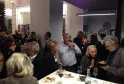Guests in business attire networking at a wine tasting event at Max Bordeaux Wine Gallery & Cellar, with charcuterie plates and wine glasses on tables.