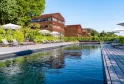 Outdoor swimming pool at Le Saint-James hotel in Bordeaux featuring red brick buildings, sun loungers, umbrellas, and wooden deck