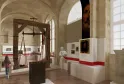 Interior of the National Customs Museum in Bordeaux displaying an exhibition with a wooden historical scale, red-banded information panels, portraits and customs objects in a vaulted gallery.