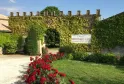 Château Monconseil-Gazin in Bordeaux with ivy-covered stone walls, red rose bushes in the foreground, and a vineyard sign