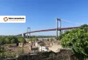 Panoramic view of the Aquitaine Bridge spanning the Garonne River with Bordeaux cityscape in the background, surrounded by traditional rooftops and greenery