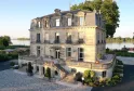 Château Grattequina in Bordeaux, a 19th-century stone mansion with mansard roofs overlooking the Garonne river, featuring ornamental terraces and wrought-iron balconies.