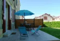 Sunny terrace at the Maison des Hôtesses in Bordeaux featuring blue loungers, blue parasol, garden furniture and wooden fence overlooking a green garden and neighboring houses