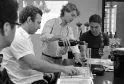 Wine tasting in Bordeaux: a sommelier pours red wine into a glass while three other people watch attentively around a table with glasses and tasting notes.