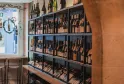 Wine display in ComplanTerra wine shop in Bordeaux, featuring bottles arranged on multiple black shelves with additional bottles displayed on top.