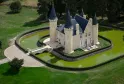 Aerial view of Château d'Agassac near Bordeaux, a medieval fortress with four conical towers surrounded by a water-filled moat, accessible via a stone bridge.