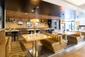 Contemporary dining room of Le Bistrot de Mériadeck in Bordeaux featuring wooden tables, golden booth seating, warm lighting, and natural wood wall panels.