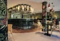Elegant bar at Ibis Styles Bordeaux Lac Bruges hotel featuring a black counter, pendant lighting, decorative floral columns, modern seating, and olive green walls.